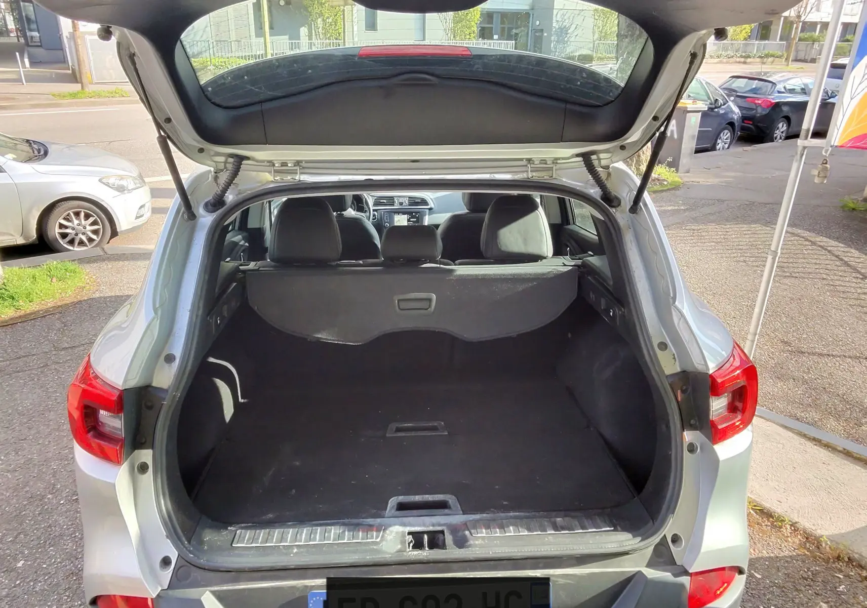 Vue arrière ouverte du Renault Kadjar gris platine métal de 2016, mettant en valeur le coffre spacieux et la lunette arrière.