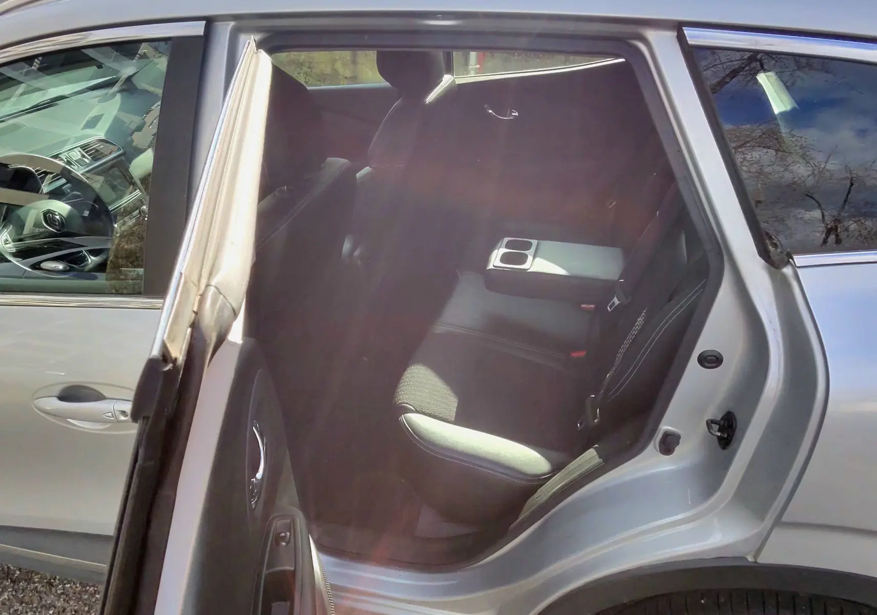 Renault Kadjar gris platine vu côté gauche arrière, porte ouverte dévoilant l'intérieur noir avec accoudoir central.