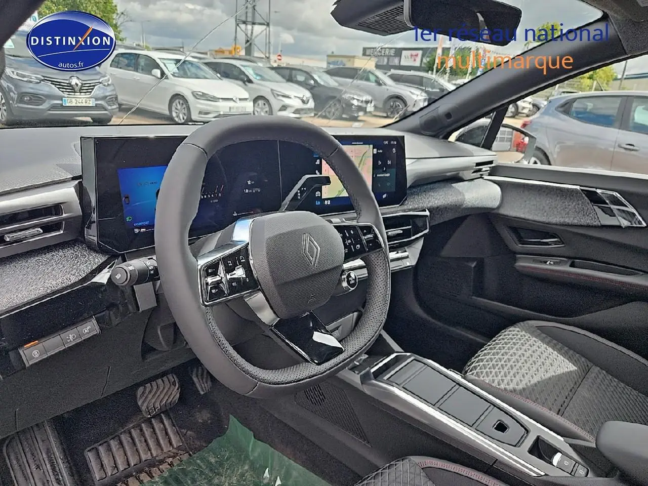 Vue intérieure avant droite de la Renault Clio VI gris rafale, volant multifonction et écran tactile large visibles.