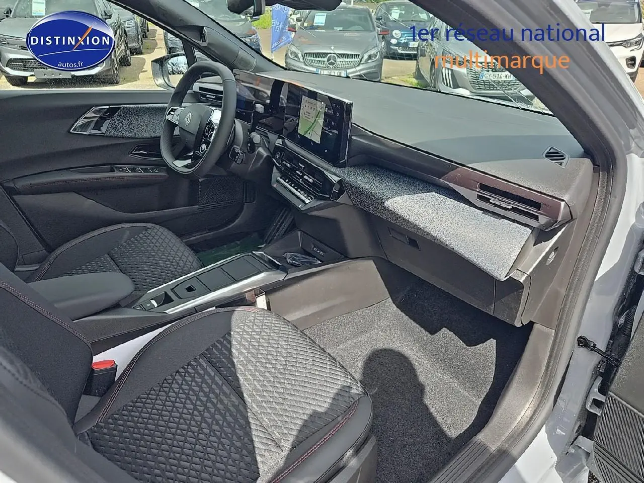 Vue intérieure côté passager avant de la Renault Clio VI gris rafale, avec tableau de bord moderne et écran tactile central.