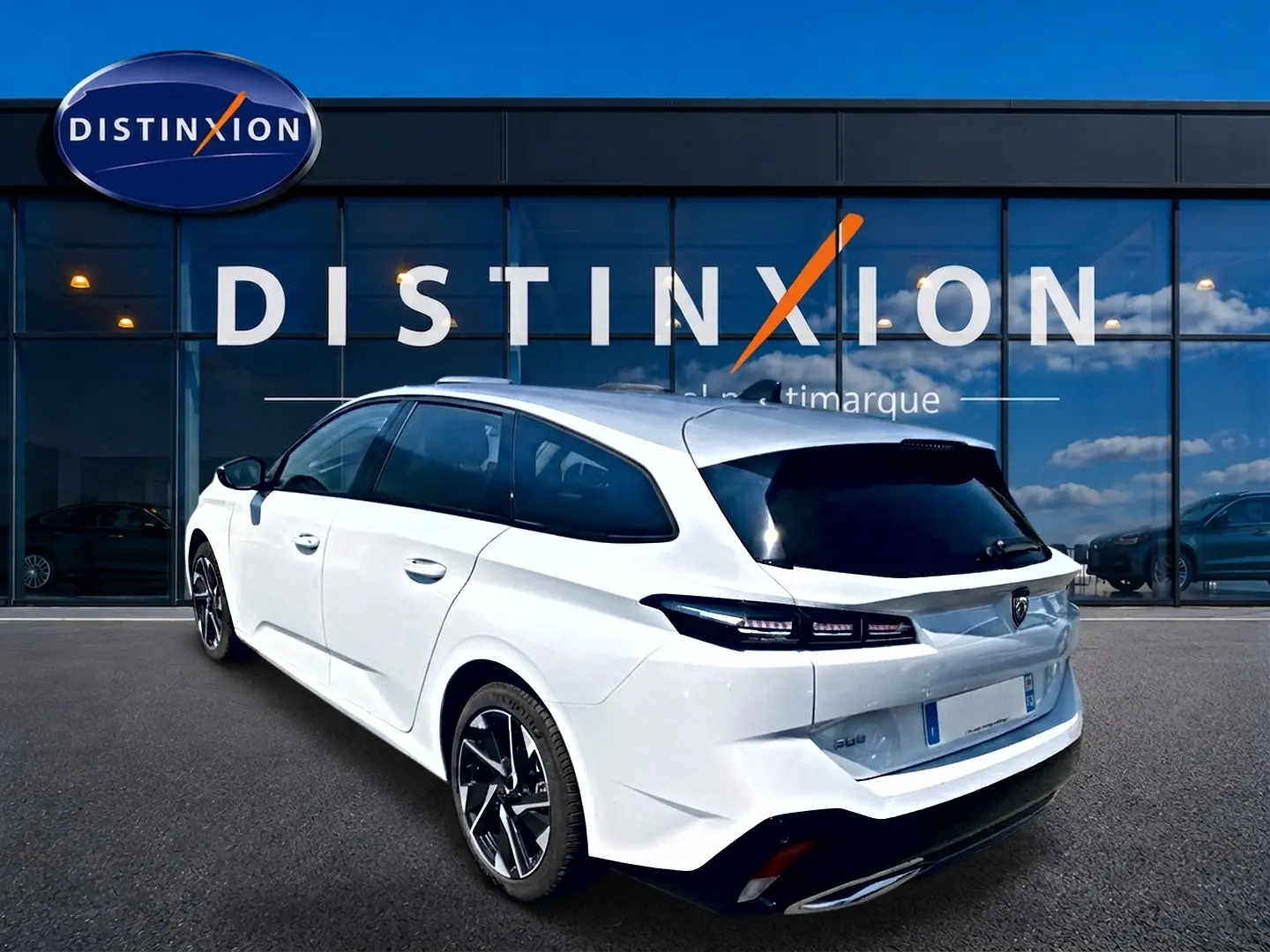Peugeot 308 SW blanche vue 3/4 arrière droit, avec vitres arrière surteintées et jantes alliage noires.