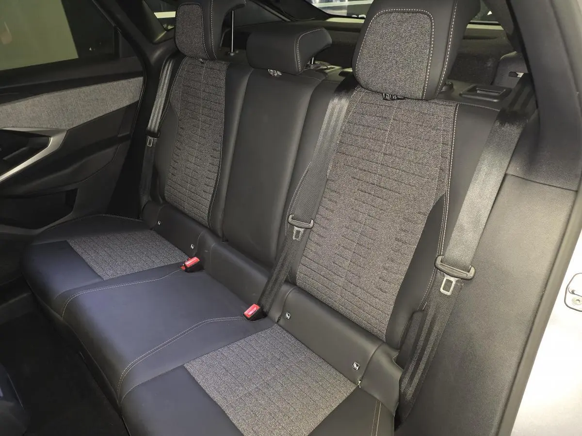 Vue intérieure de la banquette arrière du Peugeot 3008 hybride 2025, avec sellerie tissu gris et cuir noir.