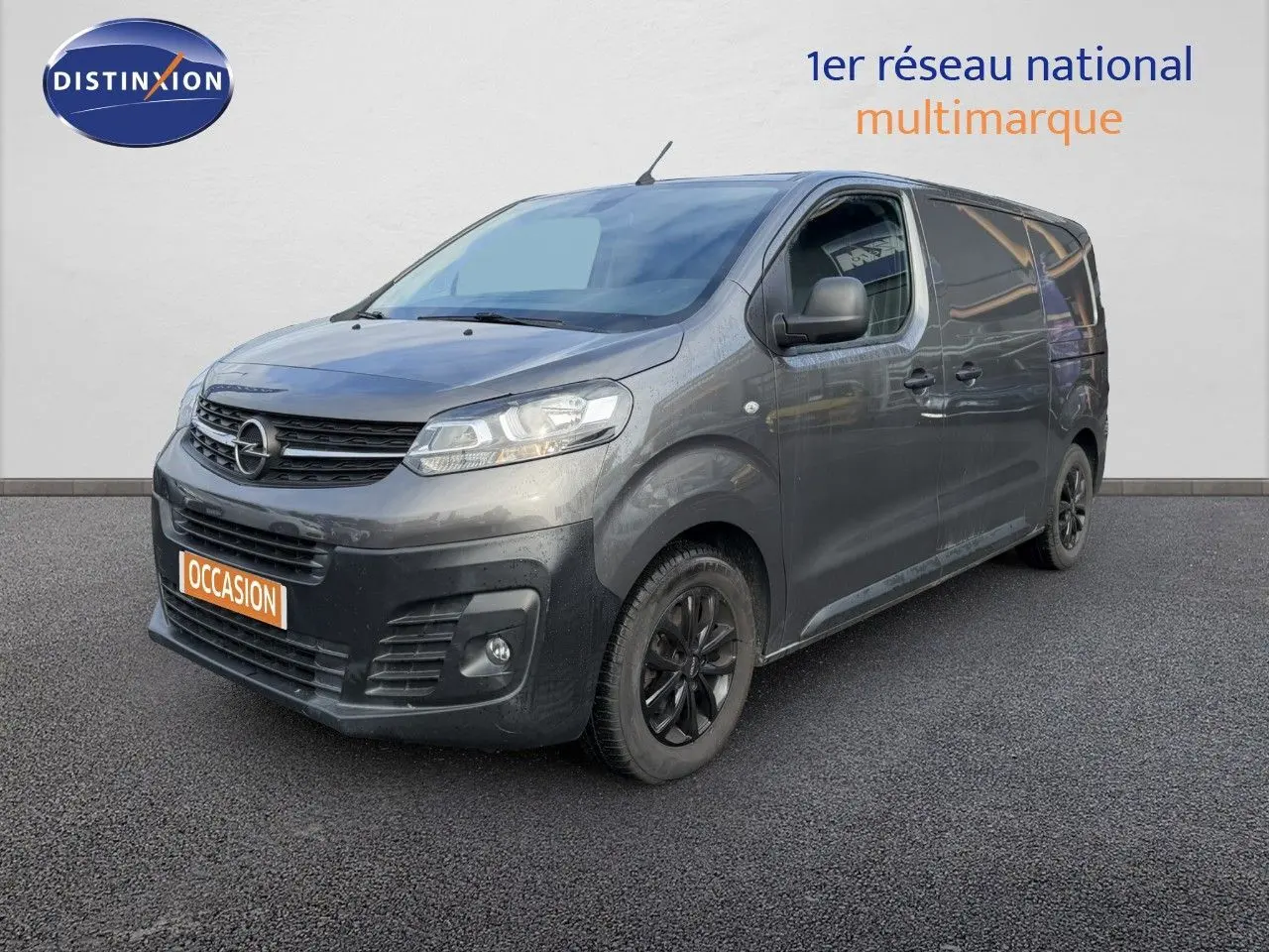 Opel Vivaro gris titane métal en 3/4 avant droit, avec jantes noires et calandre noire distinctive.