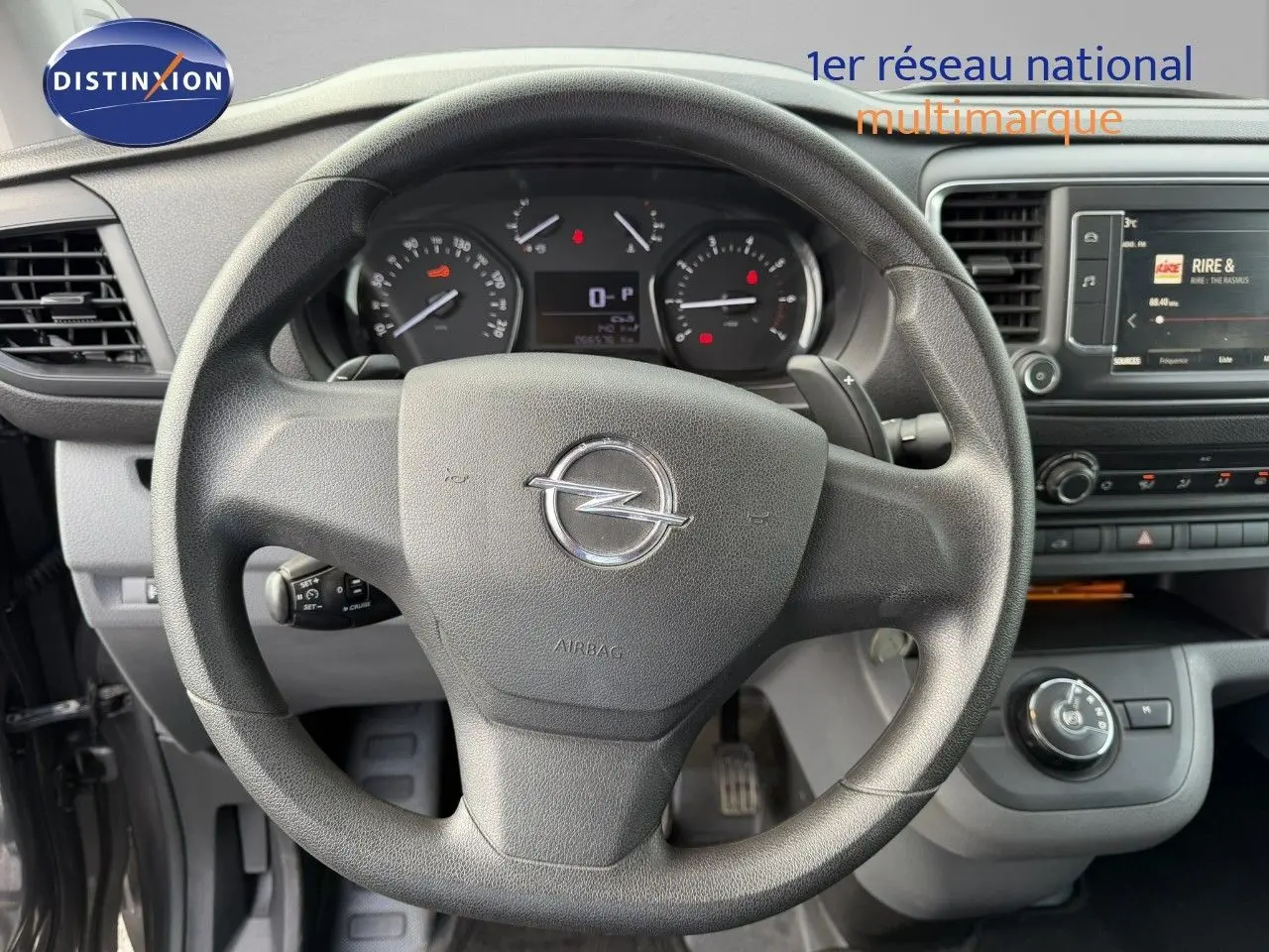 Vue intérieure centrée sur le volant Opel Vivaro 2.0 180CH gris titane, avec tableau de bord et écran multimédia visibles.
