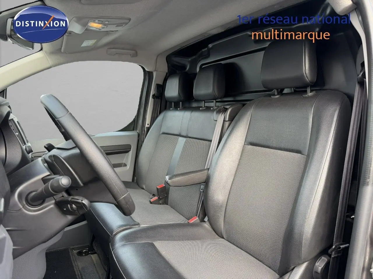 Vue intérieure côté conducteur de l’Opel Vivaro 2.0 gris titane, montrant les sièges avant en tissu et cuir noir.
