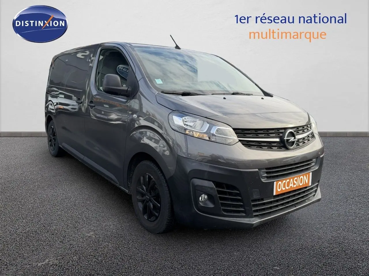 Opel Vivaro gris titane métal vu en 3/4 avant droit, fourgon utilitaire avec jantes noires et calandre distinctive.