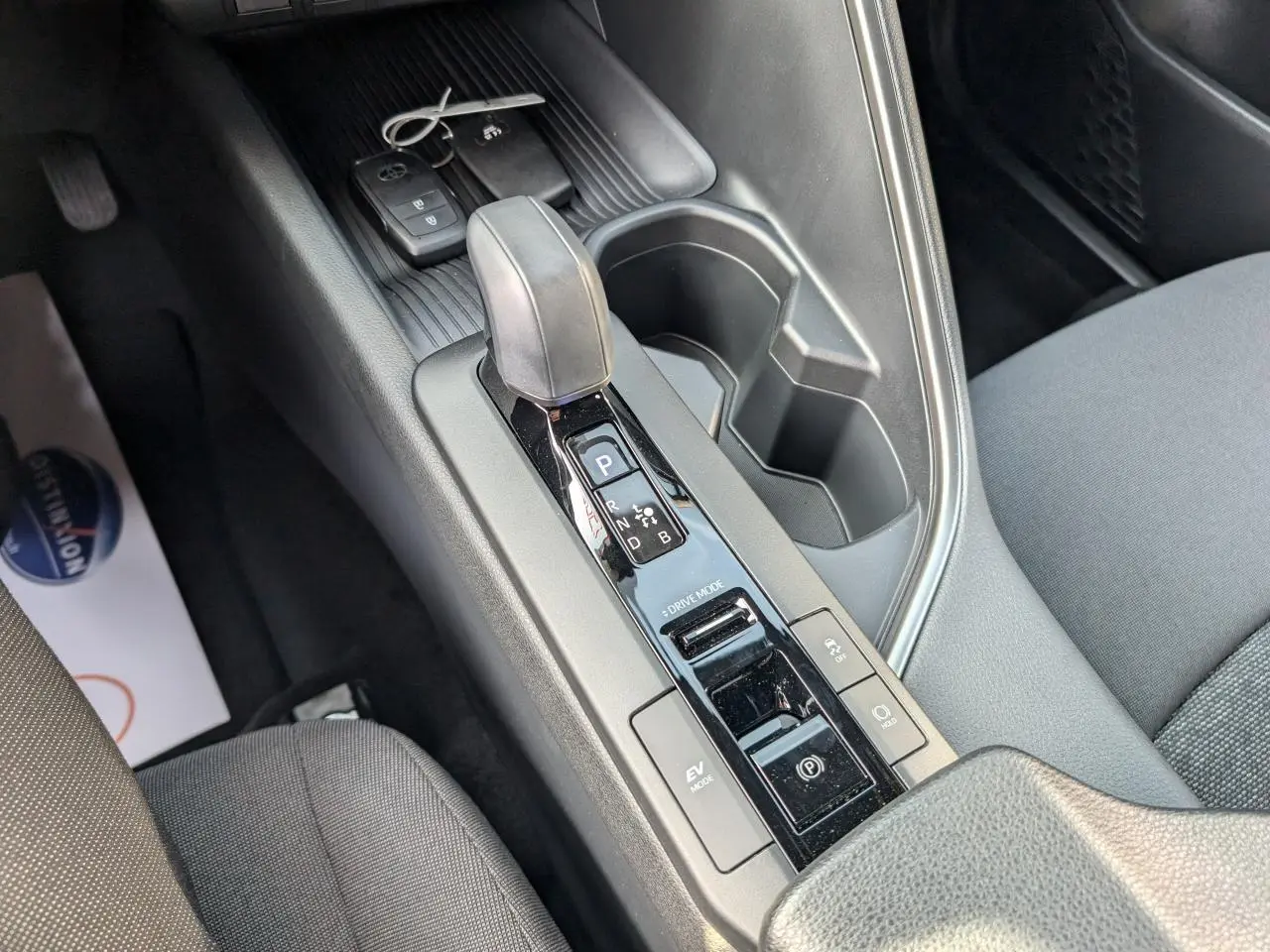 Vue rapprochée de la console centrale du Toyota C-HR 2024 hybride, avec levier de vitesse automatique et porte-gobelets.