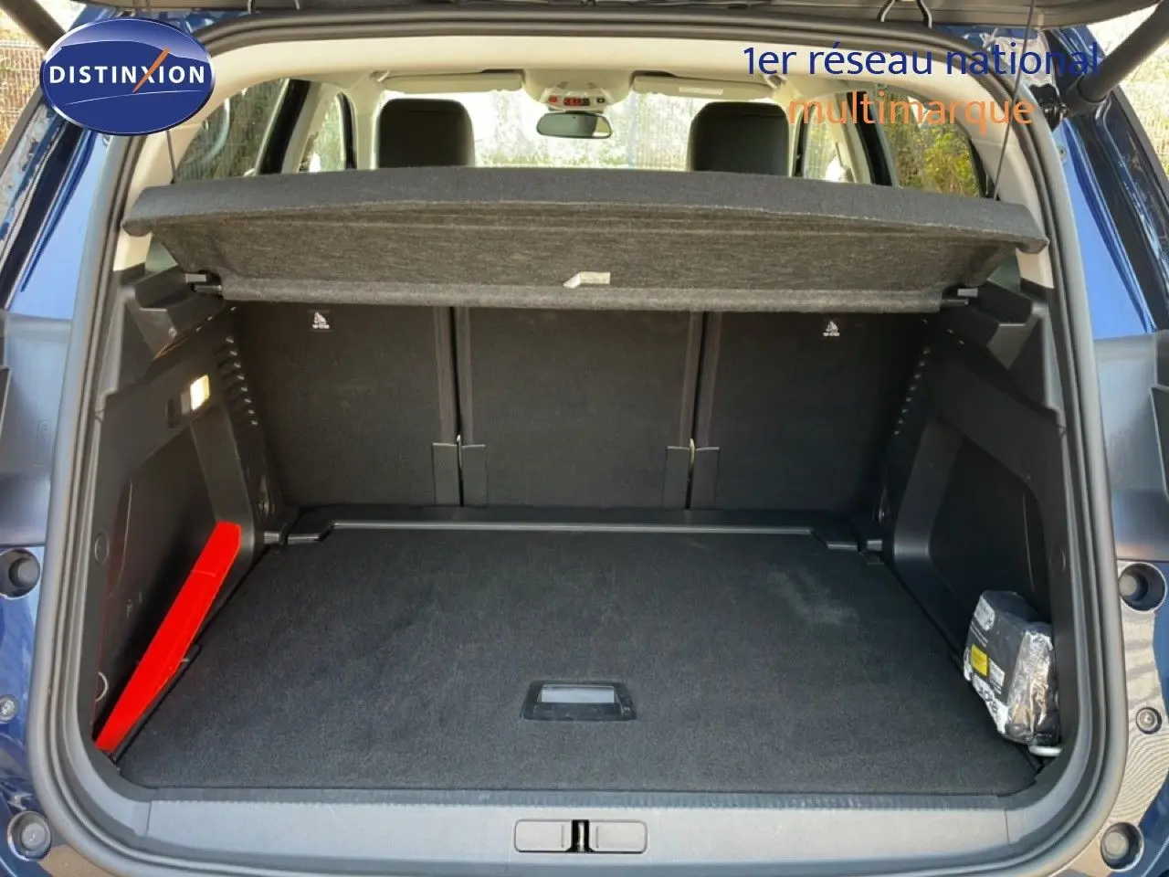 Coffre ouvert vu de l'arrière d'un Citroën C5 Aircross bleu Eclipse Metal, avec cache-bagages et tapis noir.