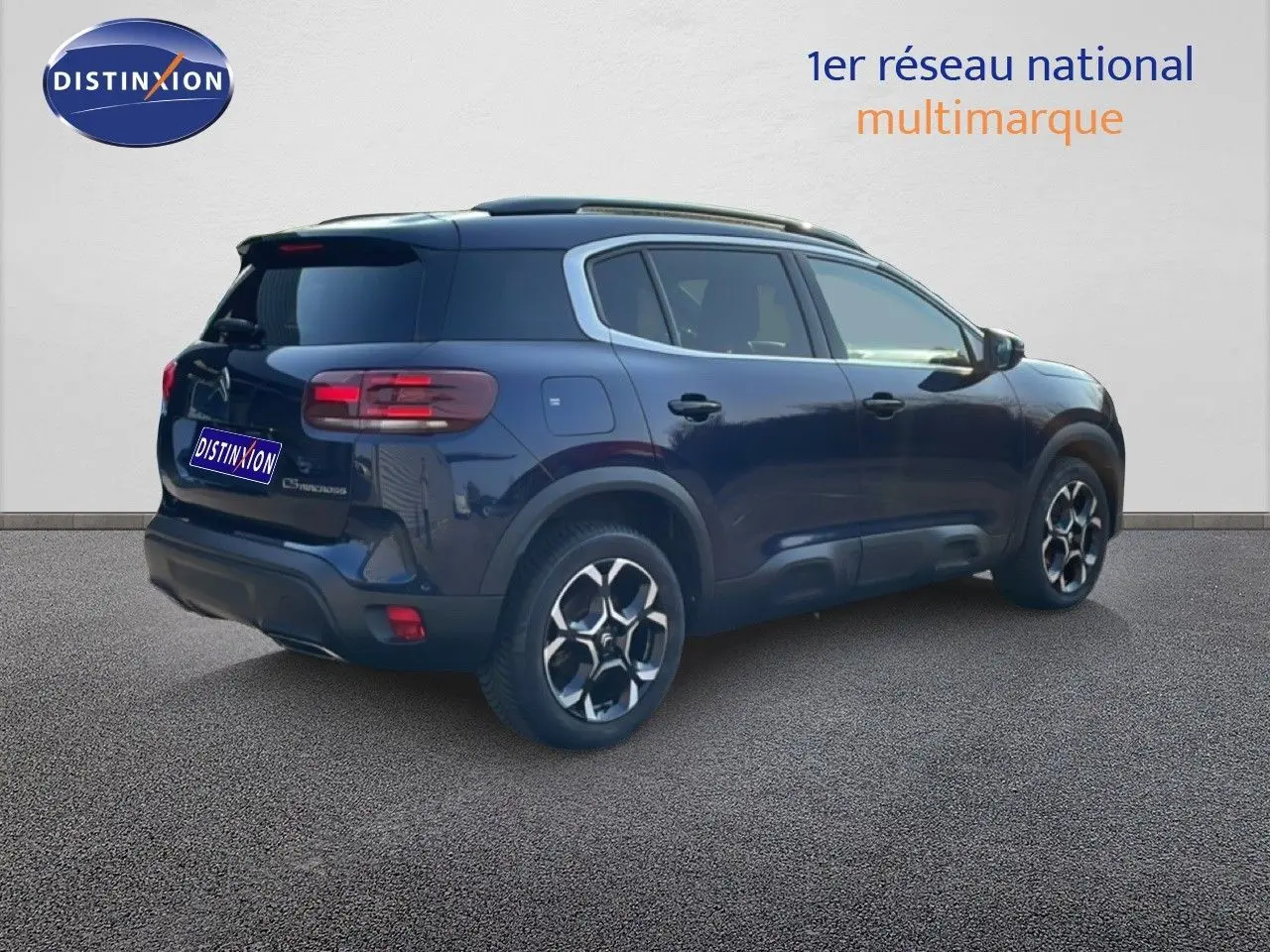 Vue 3/4 arrière droite d'un Citroën C5 Aircross 2025 bleu Eclipse Métal avec jantes bi-ton et toit noir.