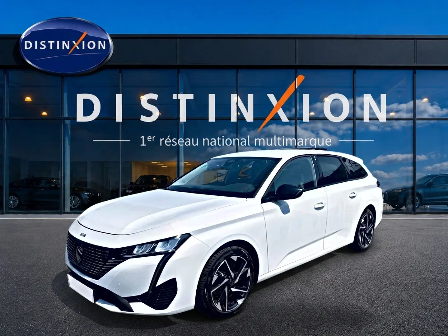 Peugeot 308 SW blanche vue en 3/4 avant droit, avec jantes alliage noires et calandre noire distinctive.