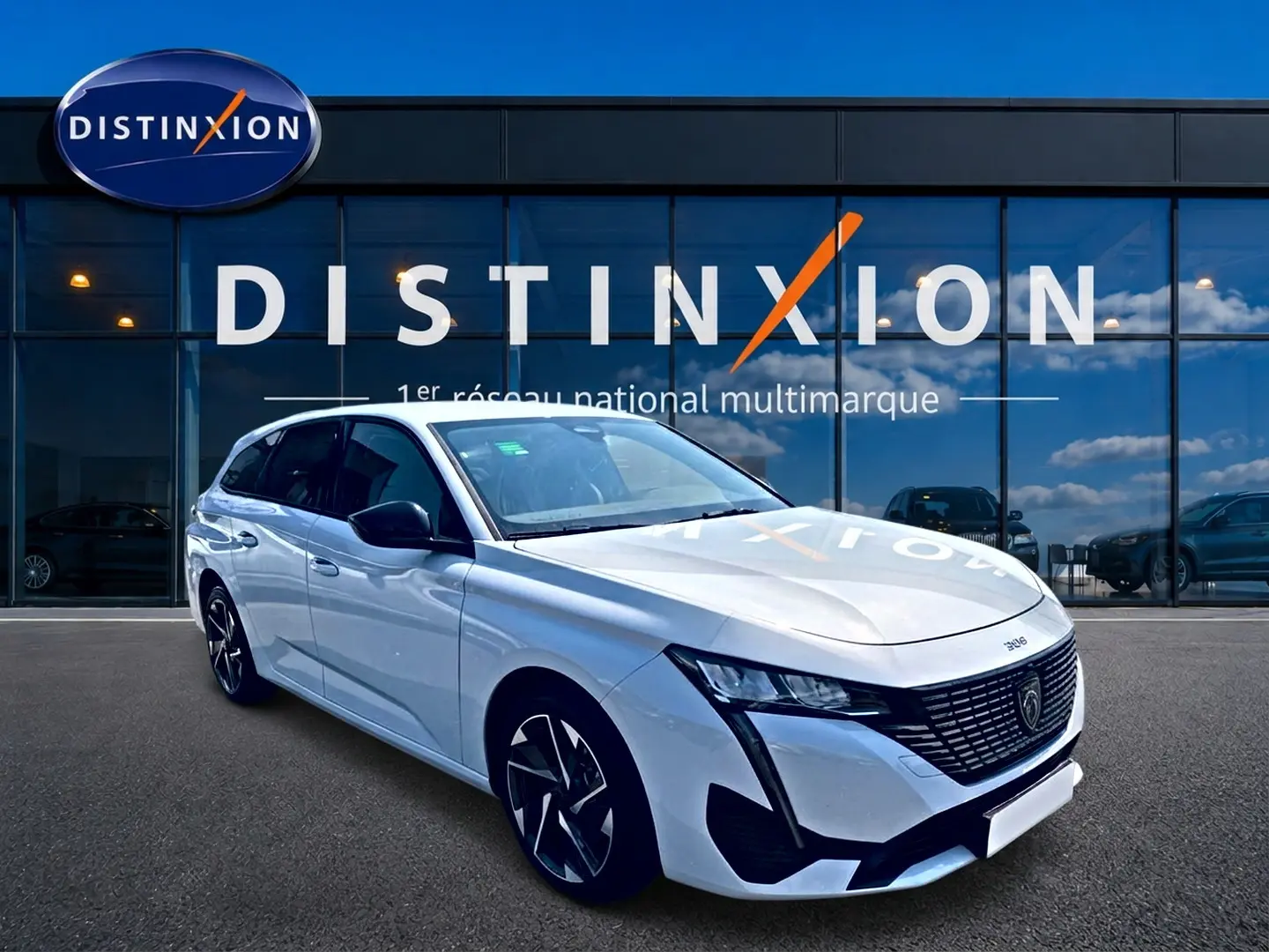 Peugeot 308 SW blanche vue en 3/4 avant droit, avec jantes alliage et calandre noire distinctive.