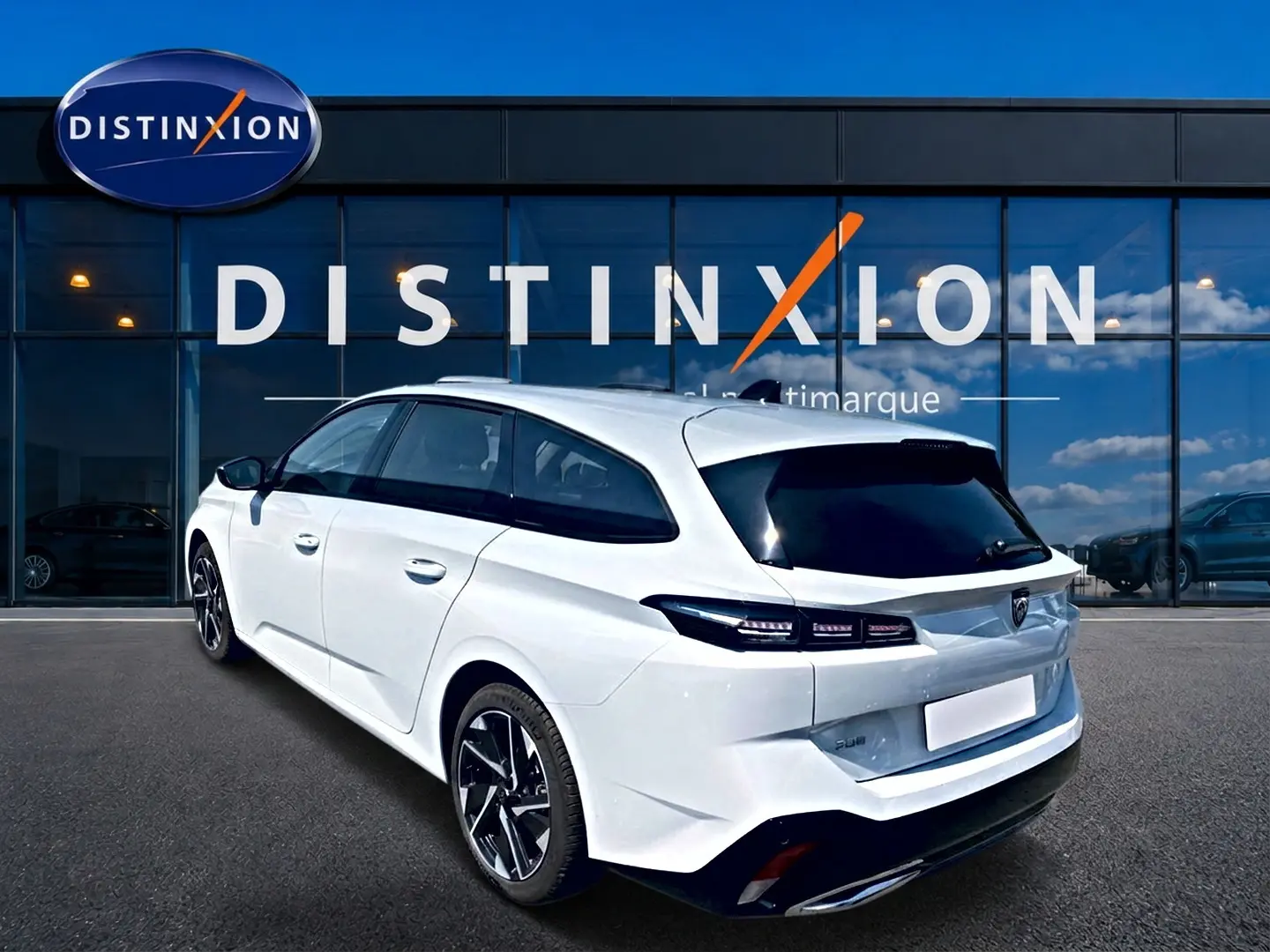 Peugeot 308 SW blanche vue 3/4 arrière droit, avec vitres arrière surteintées et jantes alliage noires.