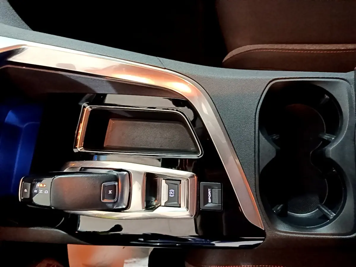 Gros plan sur la console centrale noire brillante du Peugeot 5008 gris clair, avec levier de vitesse automatique et bouton Sport.