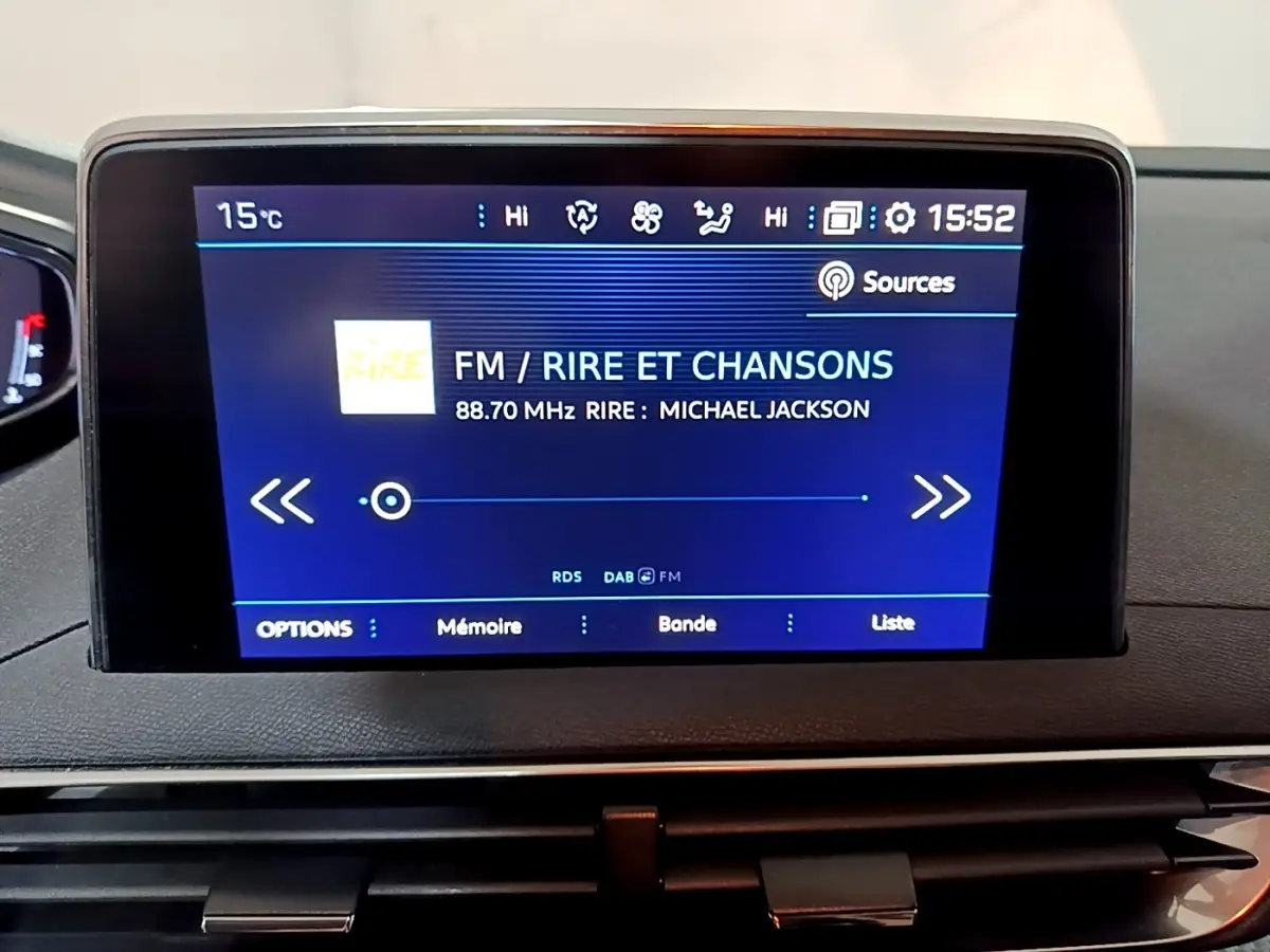 Écran tactile central du tableau de bord du Peugeot 5008 affichant une radio FM sur fond bleu.