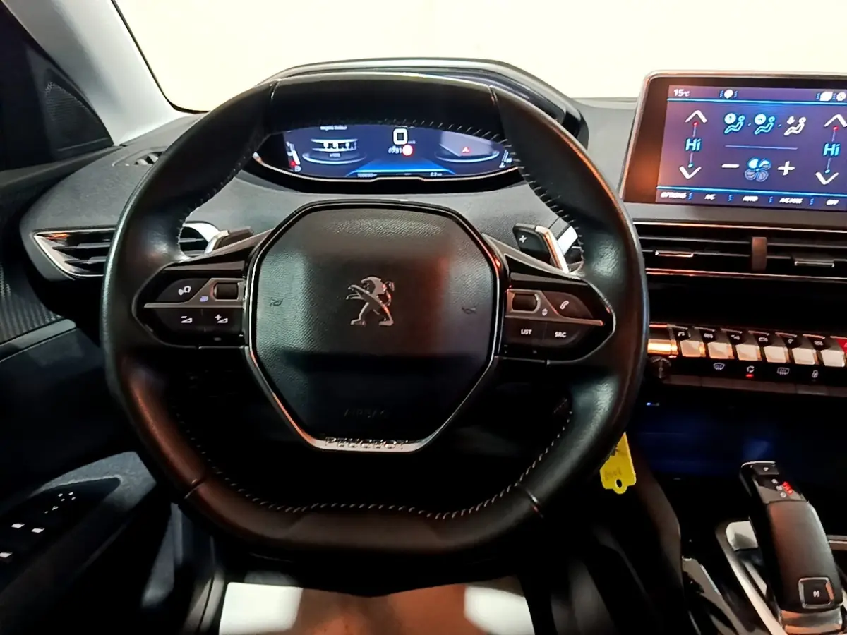 Vue rapprochée du volant cuir noir et du tableau de bord digital du Peugeot 5008 gris clair de 2020.