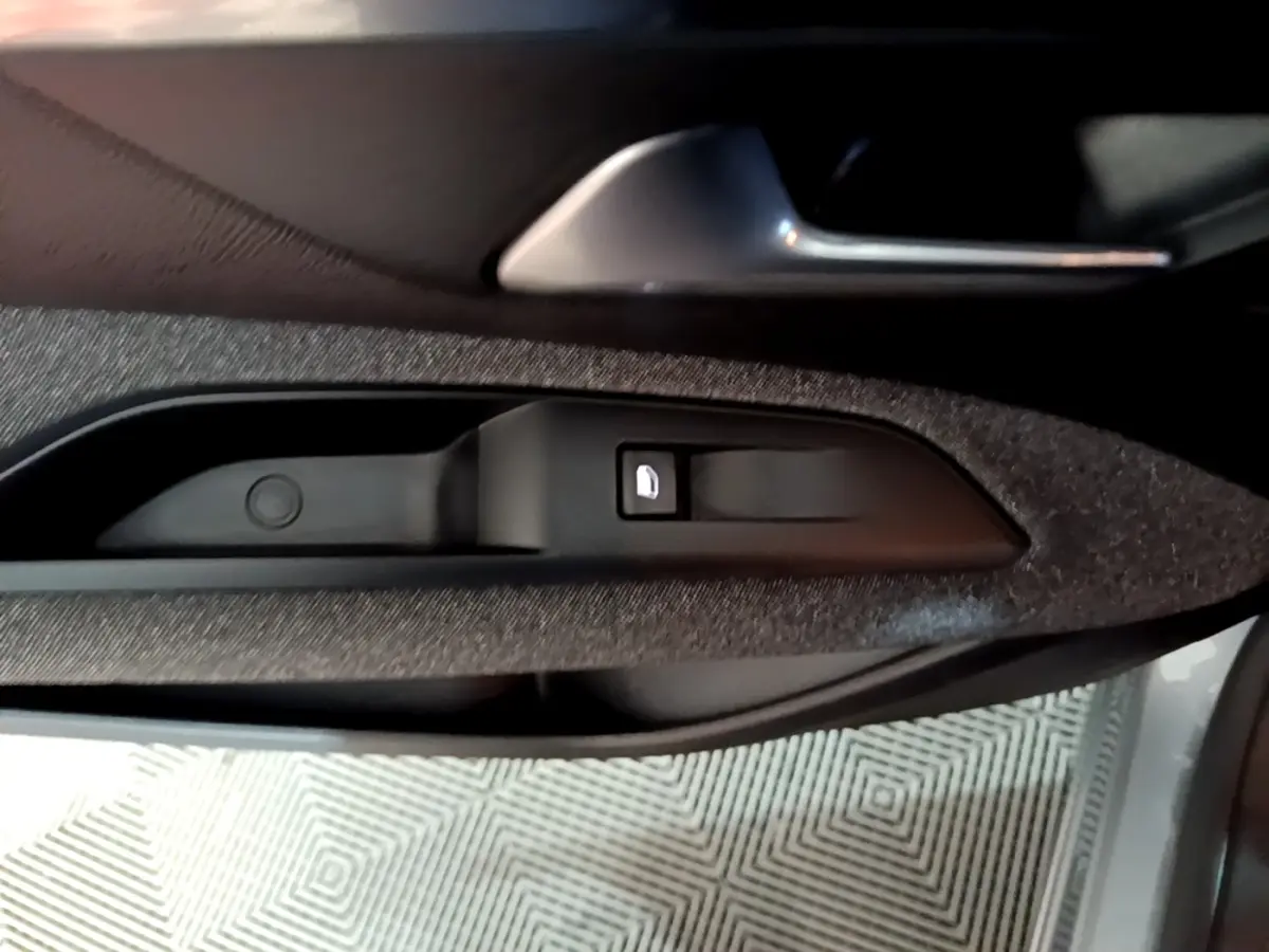 Détail de la commande de verrouillage de porte sur la portière côté conducteur d’un Peugeot 5008 gris clair.