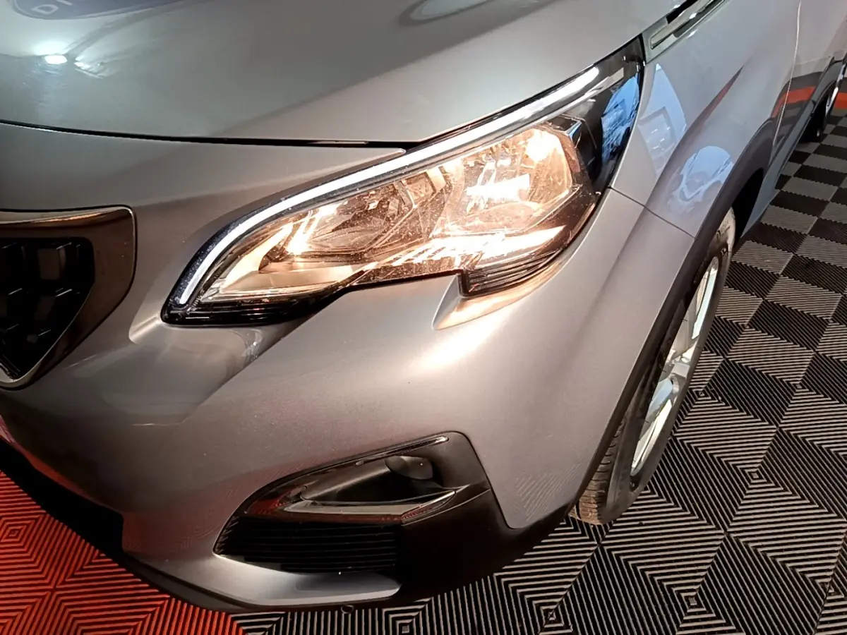 Gros plan sur l'avant droit gris clair du Peugeot 5008 2020, mettant en valeur le phare allumé et la calandre.