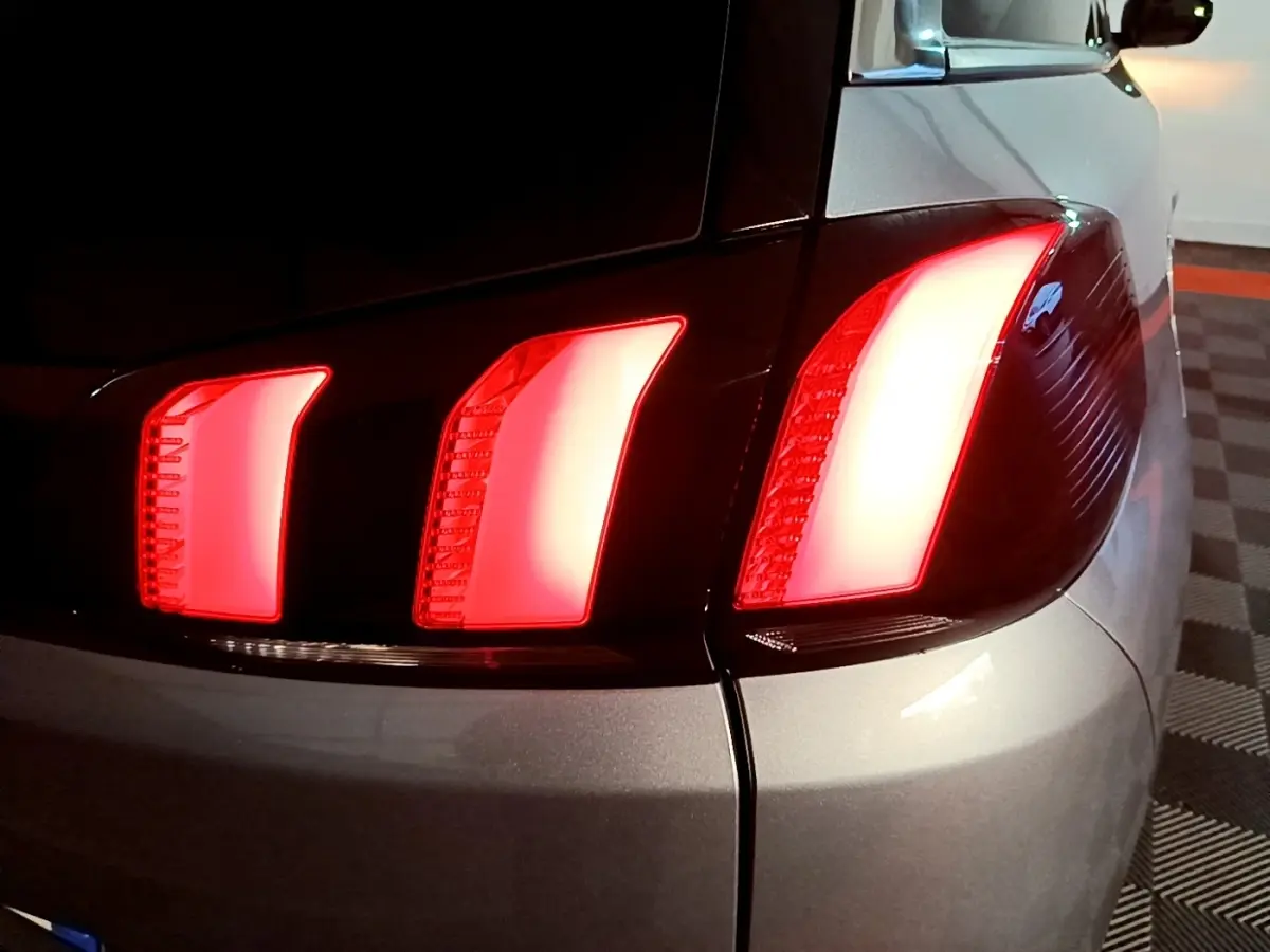 Gros plan sur le feu arrière droit allumé d’un Peugeot 5008 gris clair, vue arrière en intérieur.