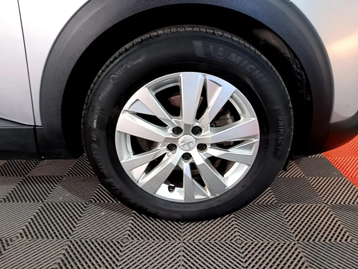 Gros plan sur la roue avant droite avec jante alliage argentée du Peugeot 5008 gris clair, détail du pneu Michelin.