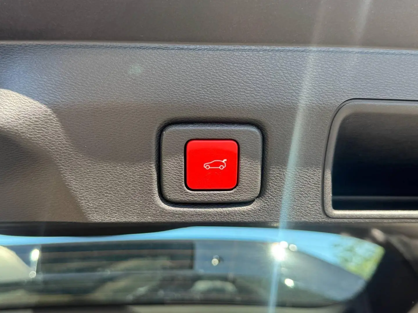 Bouton rouge d'ouverture électrique du coffre sur le panneau intérieur d'un Jeep Compass Vulcano 2026.