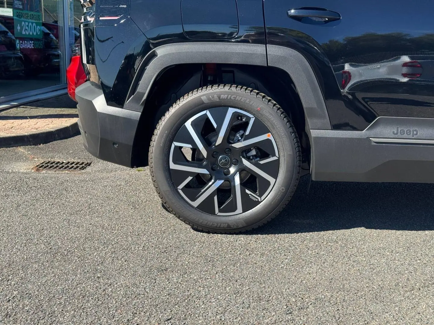 Gros plan sur la roue arrière droite et la partie latérale noire d’un Jeep Compass 2026 couleur Vulcano.