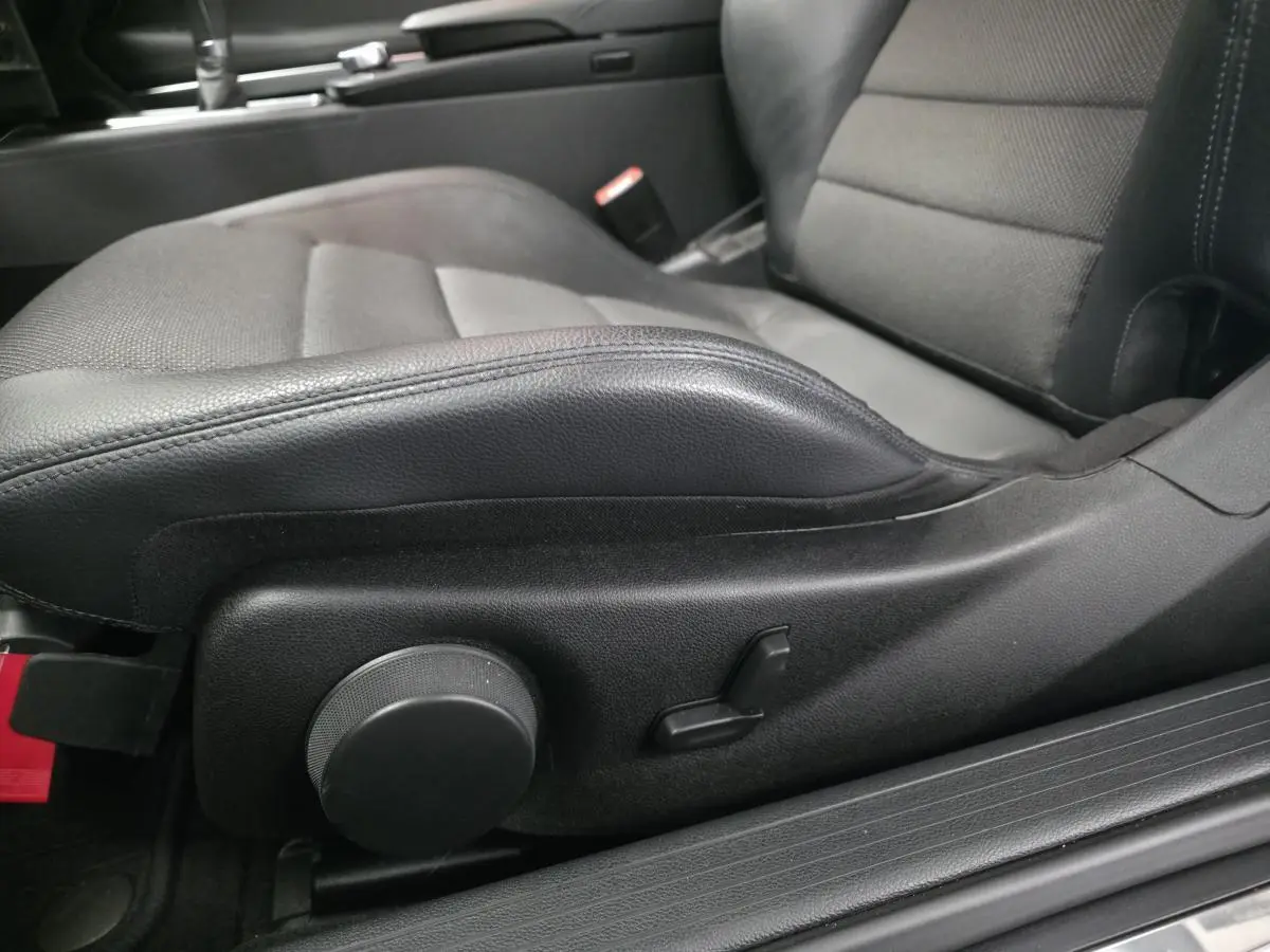 Gros plan sur le siège conducteur noir en similicuir de la Mercedes Classe E Coupé E 200, avec réglages manuels visibles.