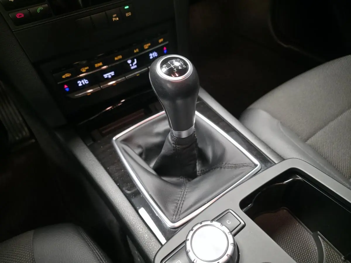 Levier de vitesses manuel en cuir noir dans la console centrale d'une Mercedes Classe E Coupé gris, vue intérieure rapprochée.