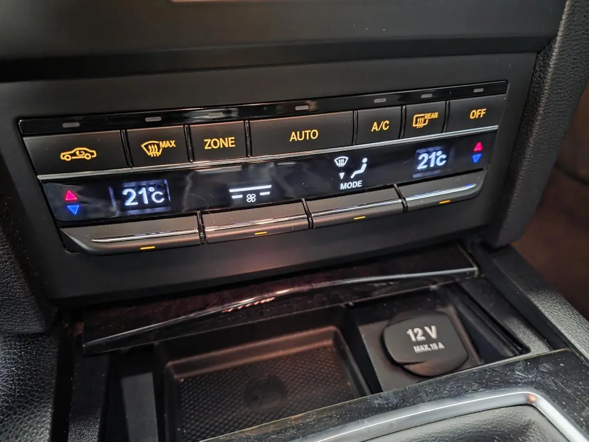 Gros plan sur la console centrale de la Mercedes Classe E Coupé 2012, affichant la climatisation automatique à 21°C.