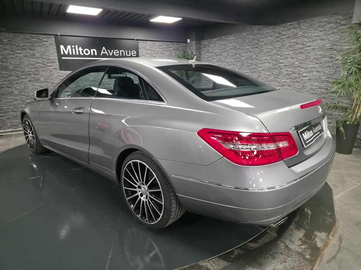 Vue 3/4 arrière droite d'un coupé Mercedes Classe E gris métallisé avec jantes alliage 19 pouces et feux arrière LED.