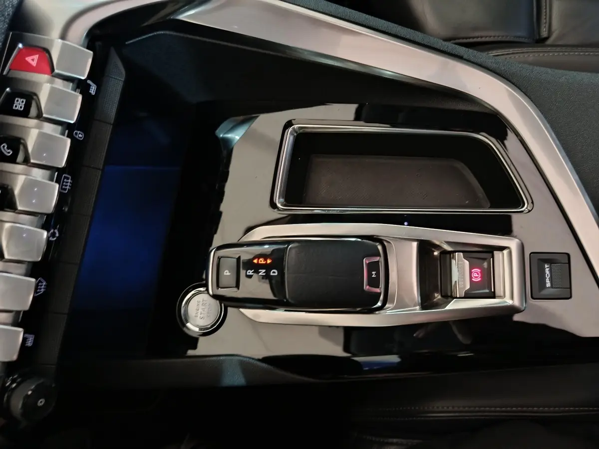 Vue rapprochée de la console centrale noire brillante du Peugeot 3008 avec levier de vitesse automatique et bouton start/stop.