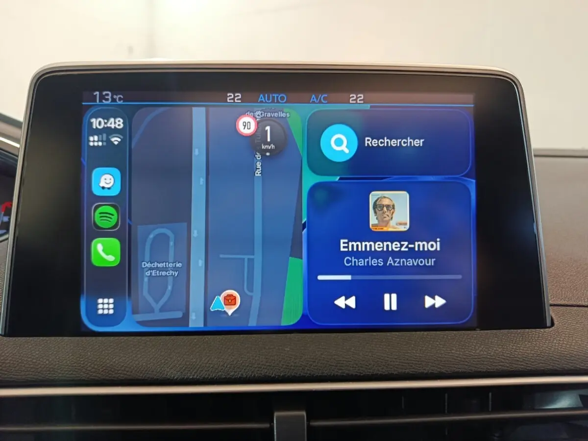 Écran tactile central du tableau de bord du Peugeot 3008 blanc, affichant navigation et musique en streaming.