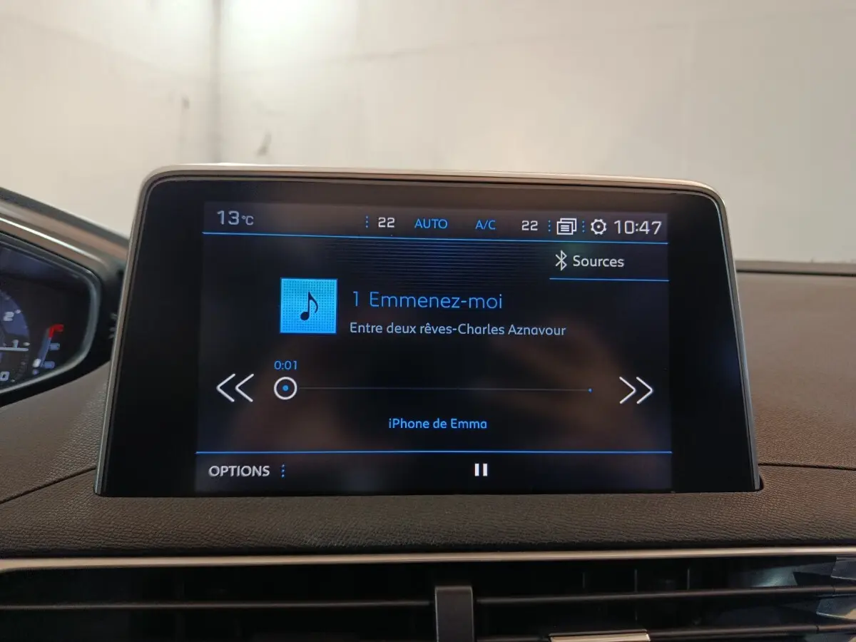Écran tactile central du tableau de bord du Peugeot 3008 blanc, affichant une musique en lecture.