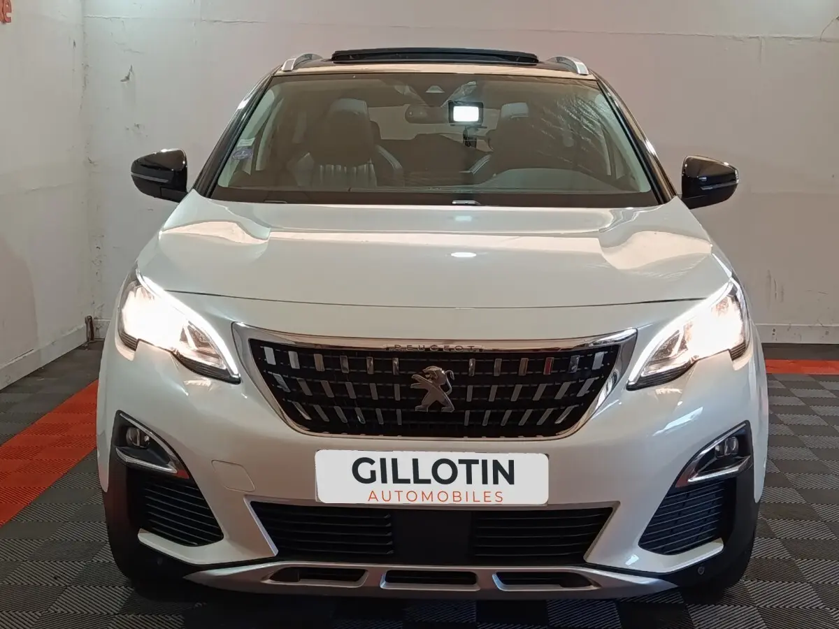 Peugeot 3008 blanc vue de face, phares allumés et calandre noire avec logo lion central.