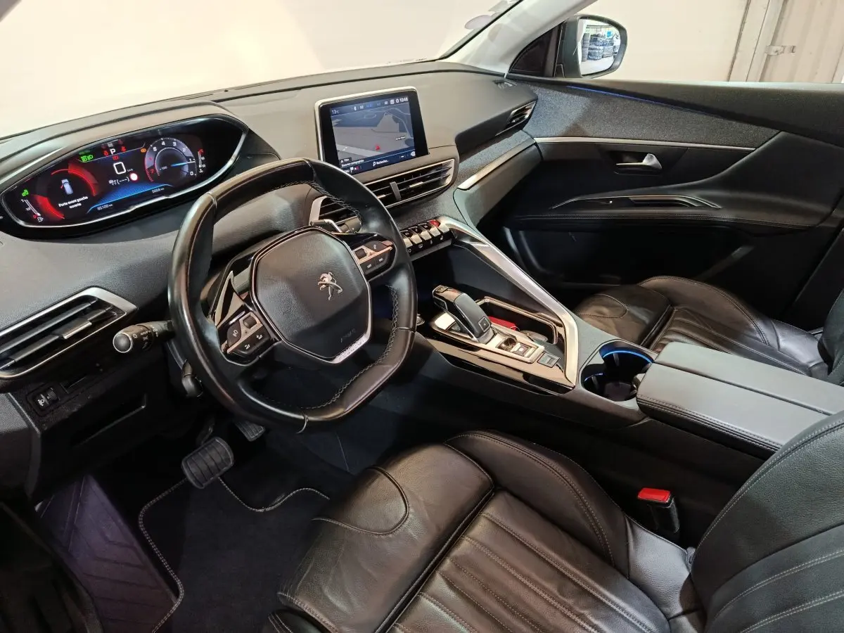 Vue intérieure côté conducteur du Peugeot 3008 blanc 2019, avec tableau de bord digital et volant cuir multifonctions.