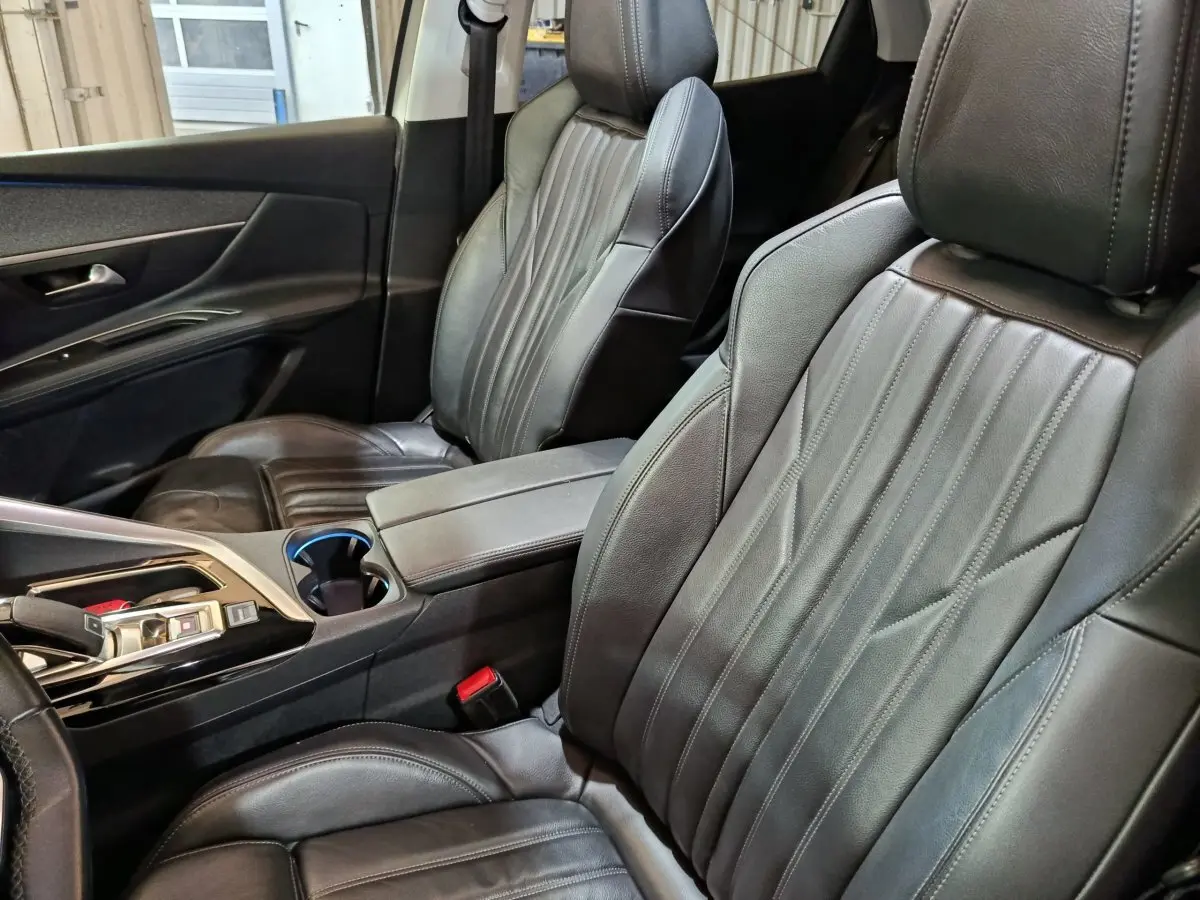 Vue intérieure côté avant droit du Peugeot 3008 2019, sièges en cuir noir et console centrale avec accoudoir.