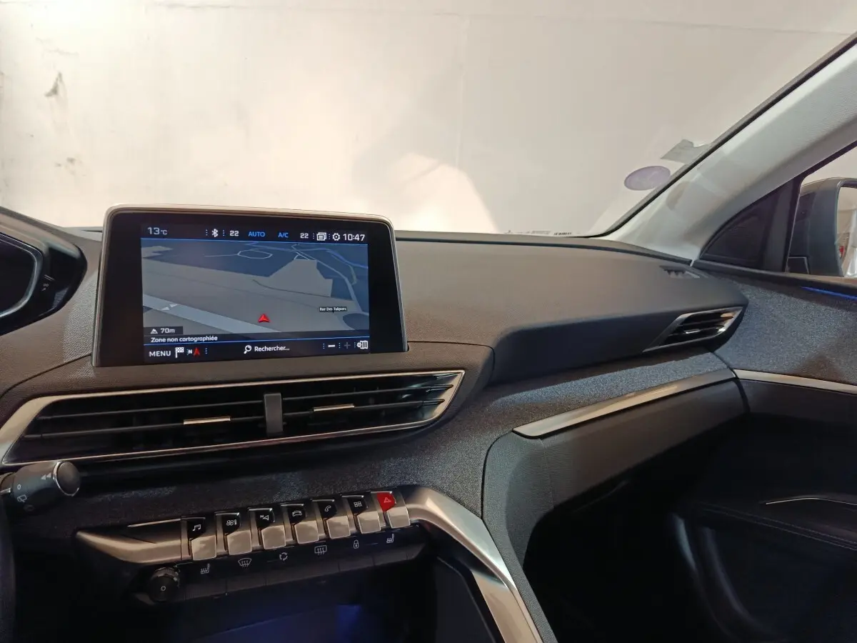 Vue intérieure côté passager du tableau de bord du Peugeot 3008 blanc avec écran tactile de navigation et commandes piano.
