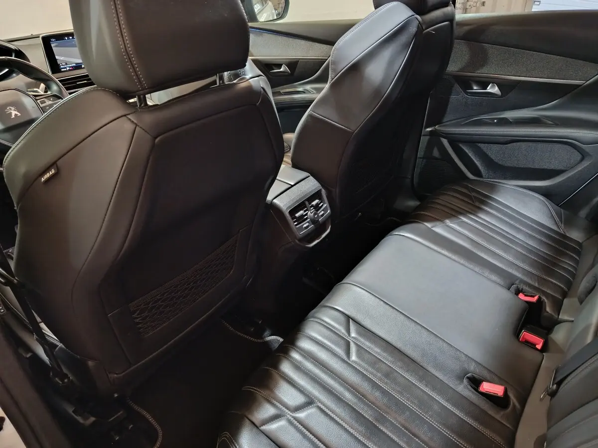 Vue intérieure arrière du Peugeot 3008 blanc, sièges en cuir noir et console centrale avec sorties d'air.