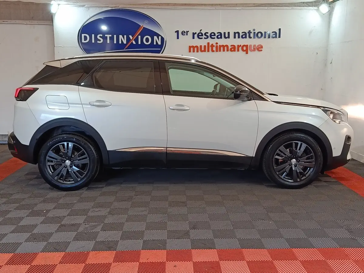 Profil côté droit d’un Peugeot 3008 blanc 2019 Puretech Allure avec jantes noires dans un showroom intérieur.