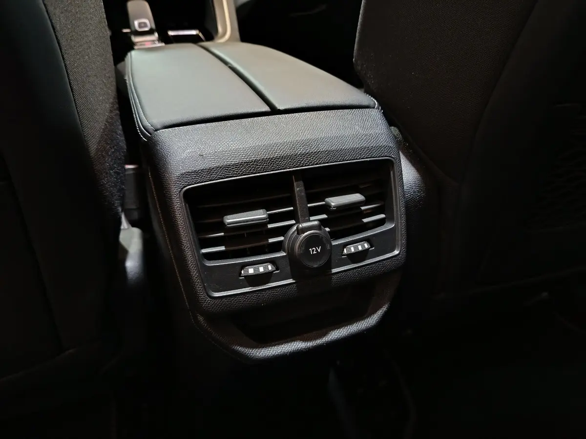 Vue rapprochée des aérateurs arrière noirs et prise 12V sur la console centrale du Peugeot 3008 blanc.