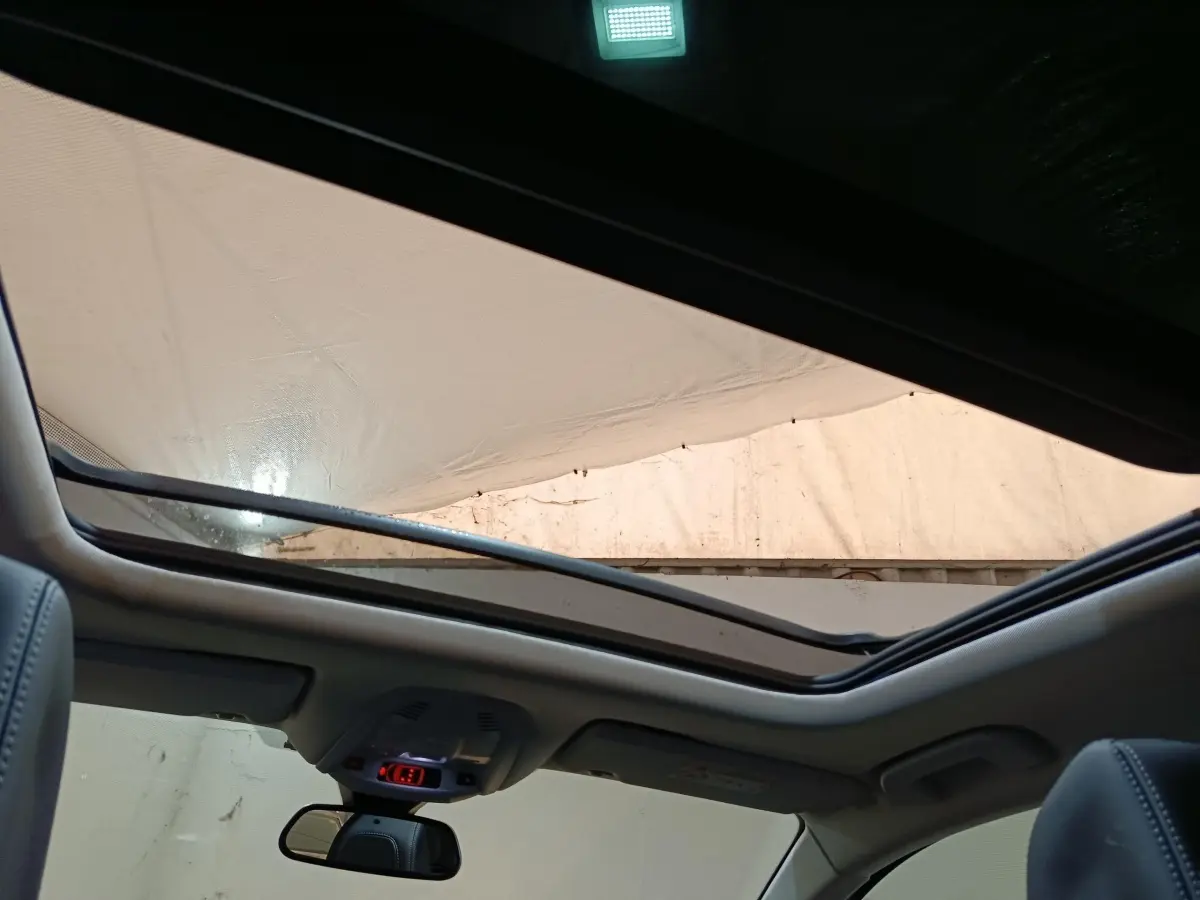 Vue intérieure du toit ouvrant panoramique du Peugeot 3008 blanc, avec ciel visible et partie des sièges avant en cuir.