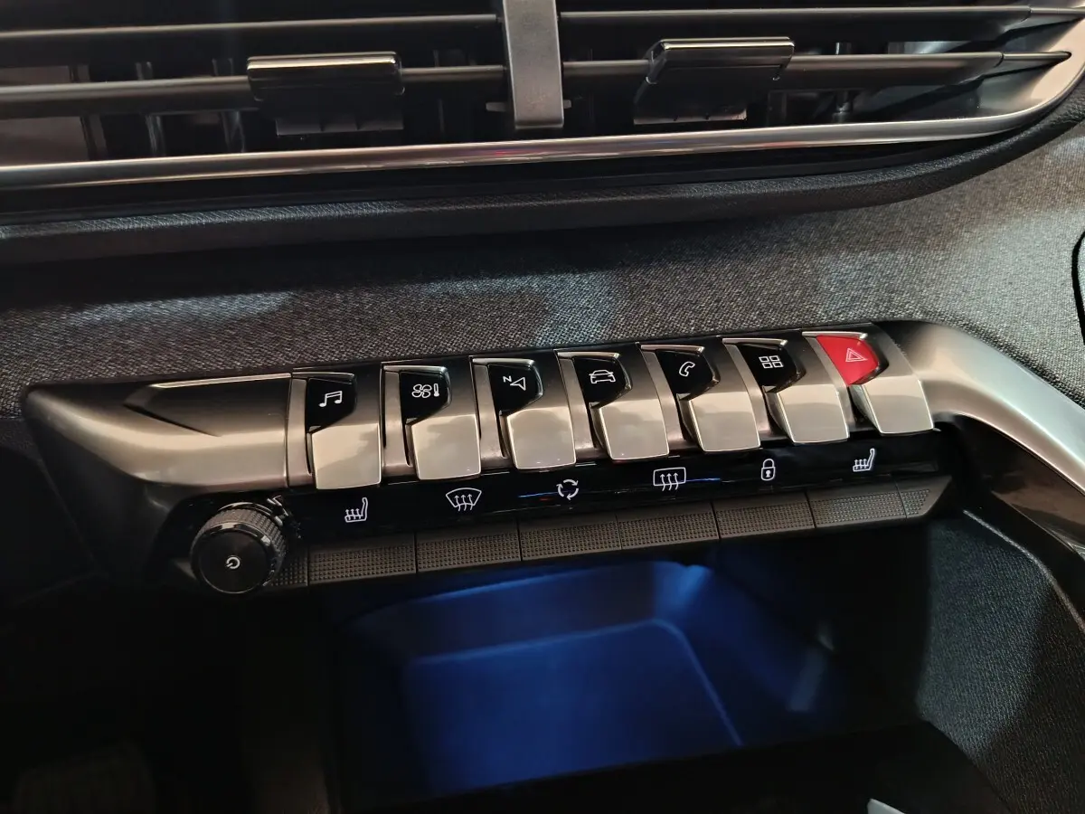 Gros plan sur la rangée de boutons argentés et noirs du tableau de bord du Peugeot 3008 blanc, version Allure 2019.