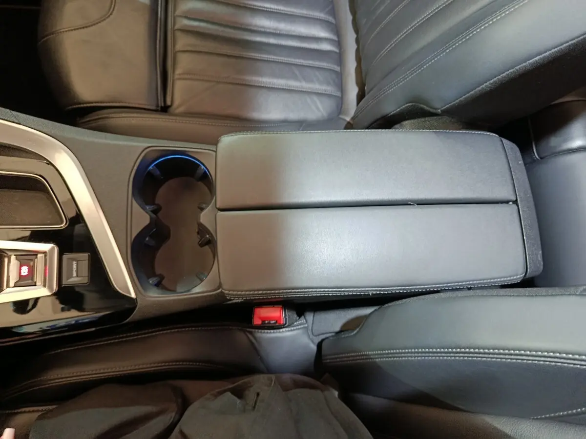 Vue plongeante sur l'accoudoir central noir et porte-gobelets du Peugeot 3008 Puretech 130 Essence 2019.