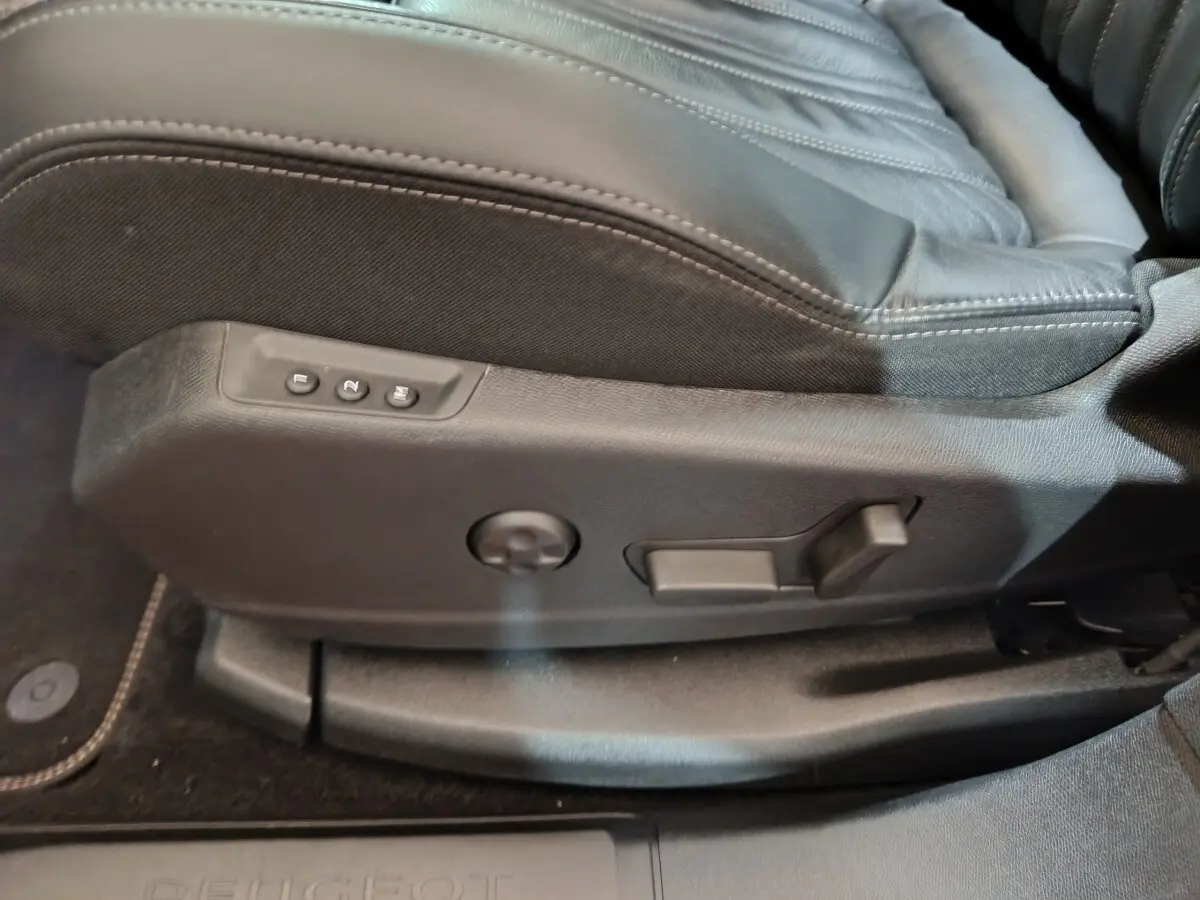 Gros plan sur les commandes de réglage électrique du siège avant droit en cuir noir du Peugeot 3008 blanc.