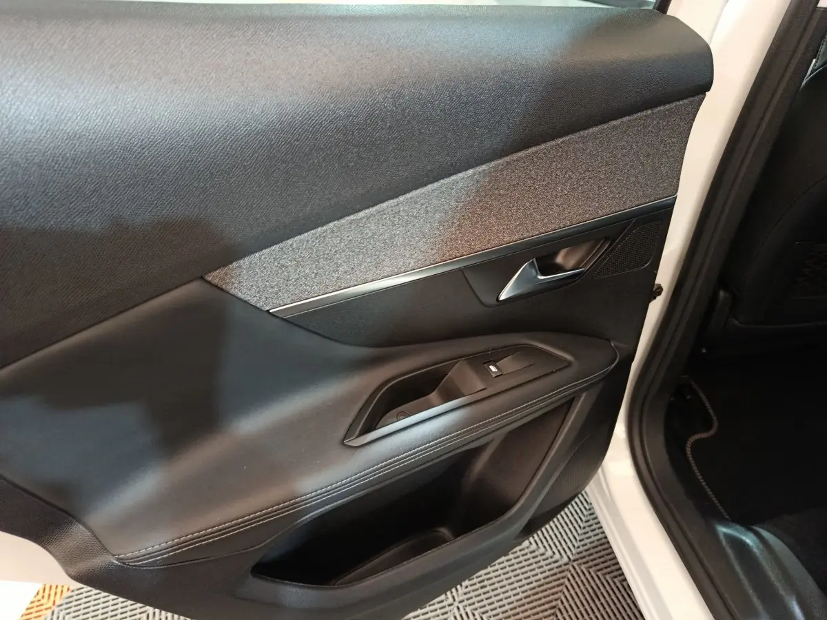 Gros plan sur la porte avant droite noire avec insert gris et poignée argentée du Peugeot 3008 blanc 2019.