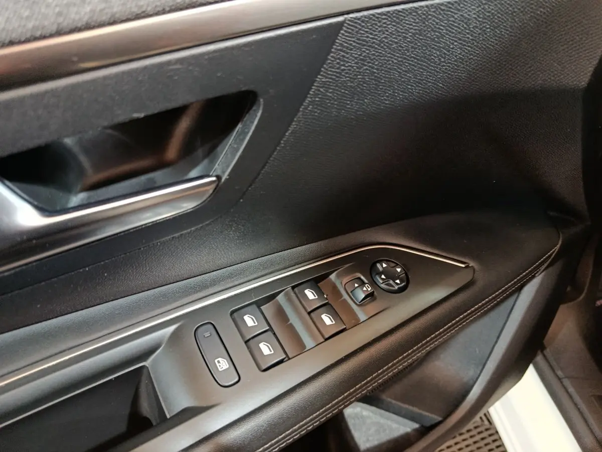 Détail des commandes des vitres et rétroviseurs sur la porte côté conducteur d’un Peugeot 3008 blanc de 2019.