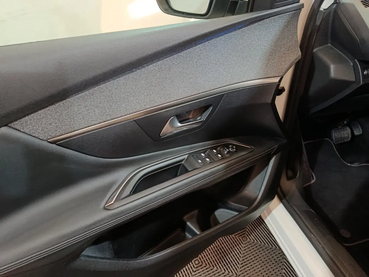 Vue intérieure côté conducteur de la porte noire avec commandes électriques sur Peugeot 3008 blanc 2019.