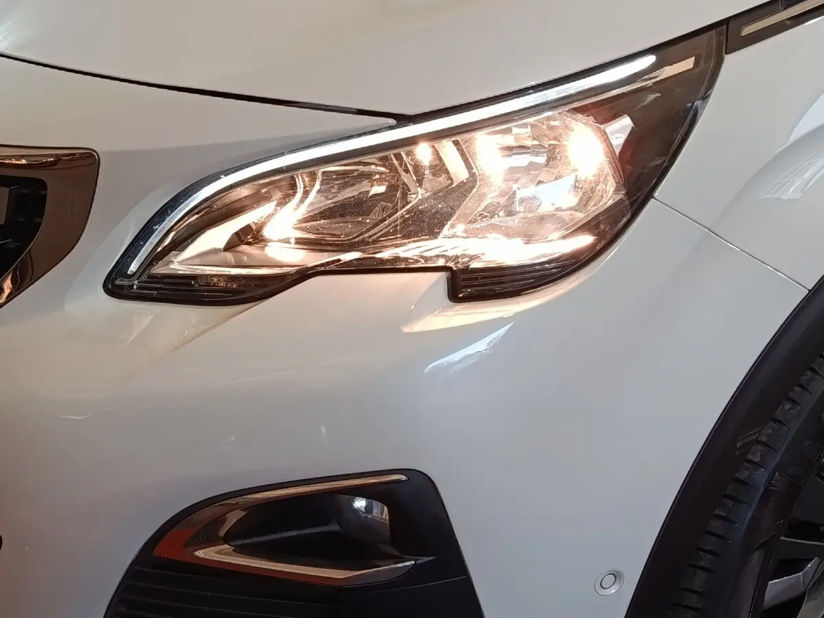 Gros plan sur l'avant droit blanc du Peugeot 3008 avec phare allumé et antibrouillard visible.
