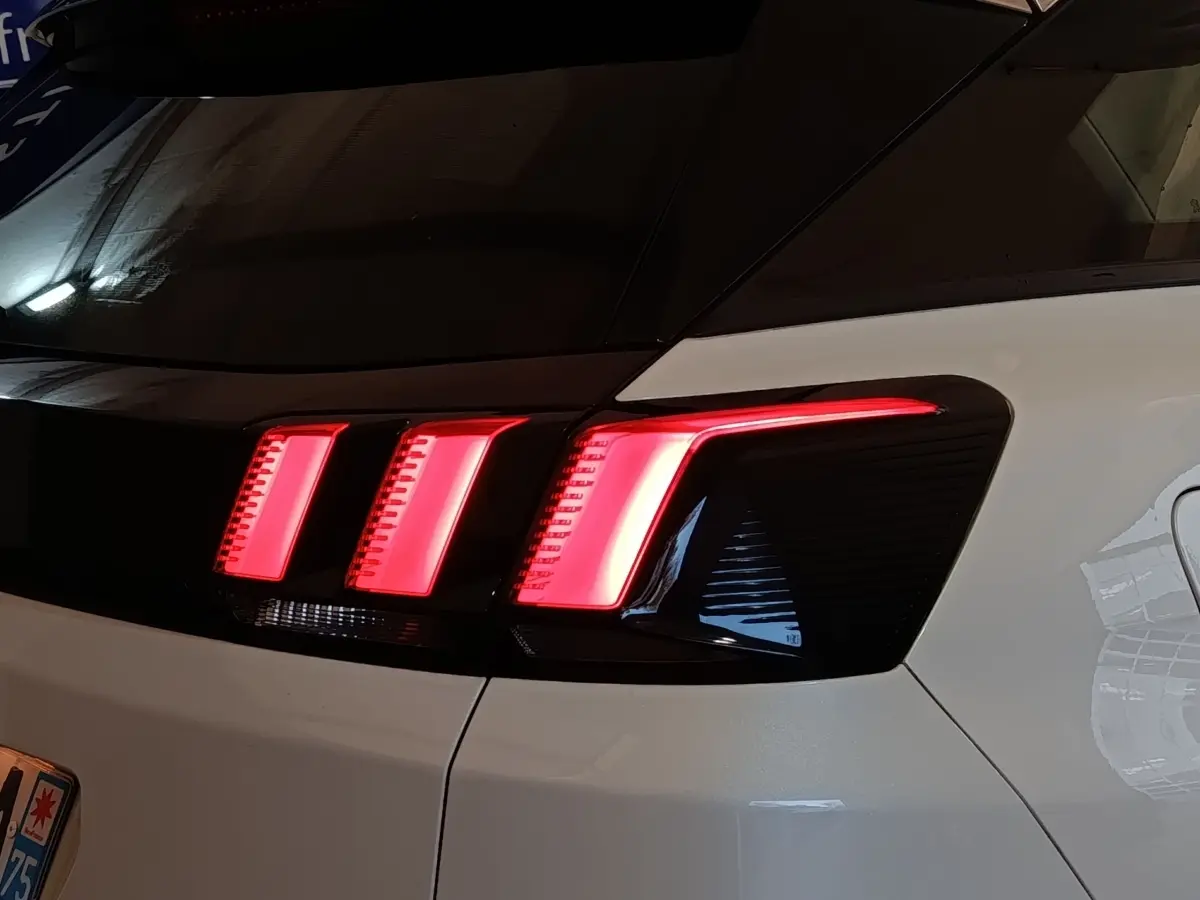 Feu arrière droit allumé d’un Peugeot 3008 blanc, vue en gros plan sur la partie arrière du véhicule.