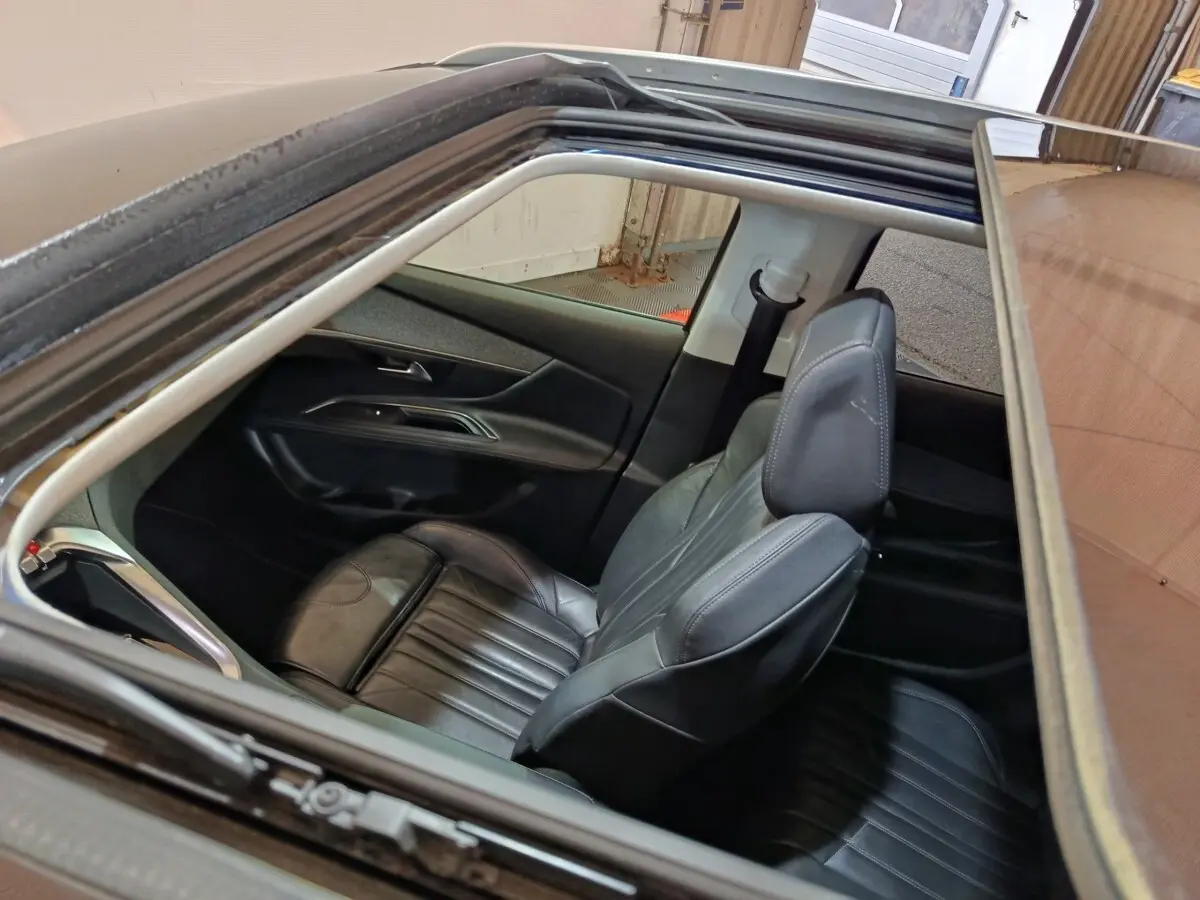 Vue intérieure par le toit ouvrant du siège avant droit en cuir noir du Peugeot 3008 blanc Puretech 2019.