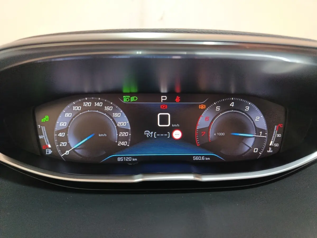 Vue rapprochée du tableau de bord numérique du Peugeot 3008 blanc, affichant vitesse, compte-tours et témoins lumineux.